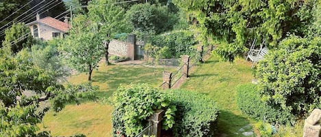 Een landelijk landschap met een stenen huis, weelderige begroeiing en een helder uitzicht op een vallei in de verte.