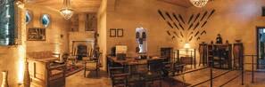 Un interior histórico con chimenea, muebles de madera y una colección de espadas colgadas en la pared.
