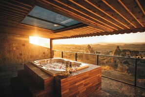 A wooden spa area with a hot tub, wine bottles, and glasses, overlooking a mountainous landscape. - Harem Suites Cappadocia (Nevsehir)