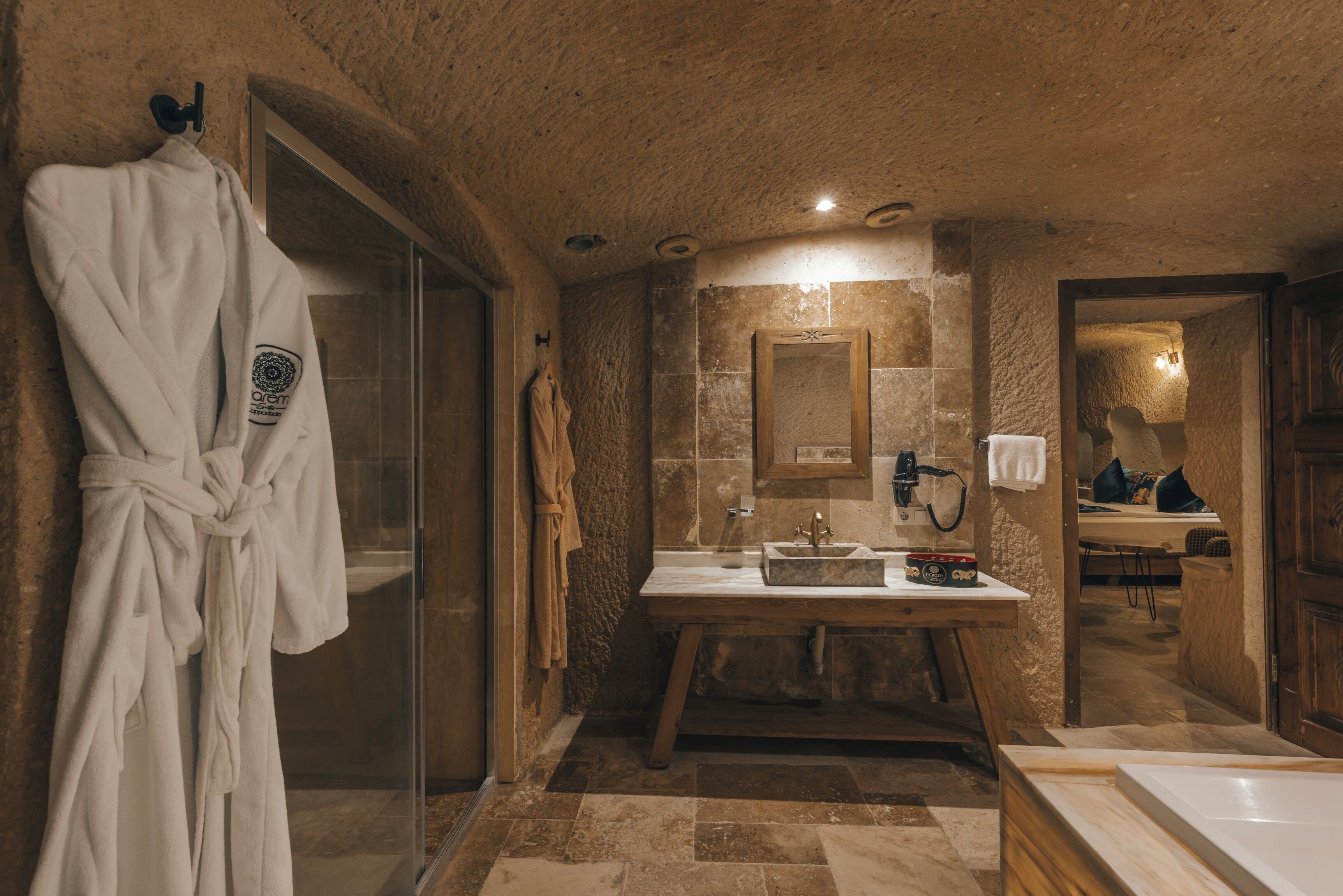 Un baño rústico con pared de piedra, tocador de madera y cabina de ducha de vidrio.