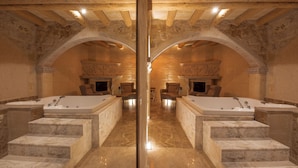 Um banheiro luxuoso com duas banheiras grandes, degraus de mármore e paredes de pedra.