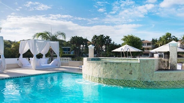 A swimming pool with a white canopy and lounge chairs, surrounded by palm trees and a clear sky. - Luxury all- inclusive villa w/ private chef (Puerto Plata)
