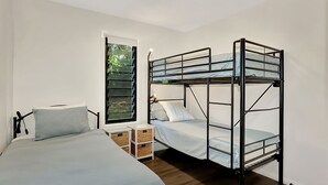 A room with a bunk bed, a single bed, a window with blinds, and a bedside table with a lamp. - Hibiscus Hideaway Valla Beach 4BR home w/ two verandahs (Valla Beach)