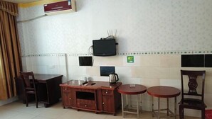 A small kitchen with a wooden cabinet, two stools, a table, and a television mounted on the wall. - Yuxing Hostel (Jieyang)