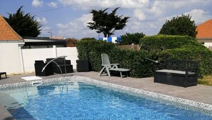 Piscina rectangular con borde de azulejos, rodeada por una cubierta de madera.