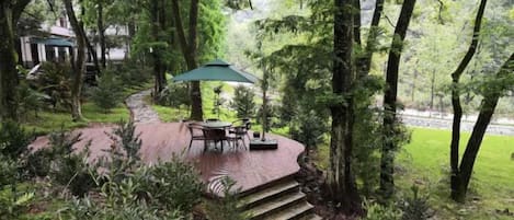 Un patio con mesa y sillas, rodeado de árboles y un sendero de ladrillos.