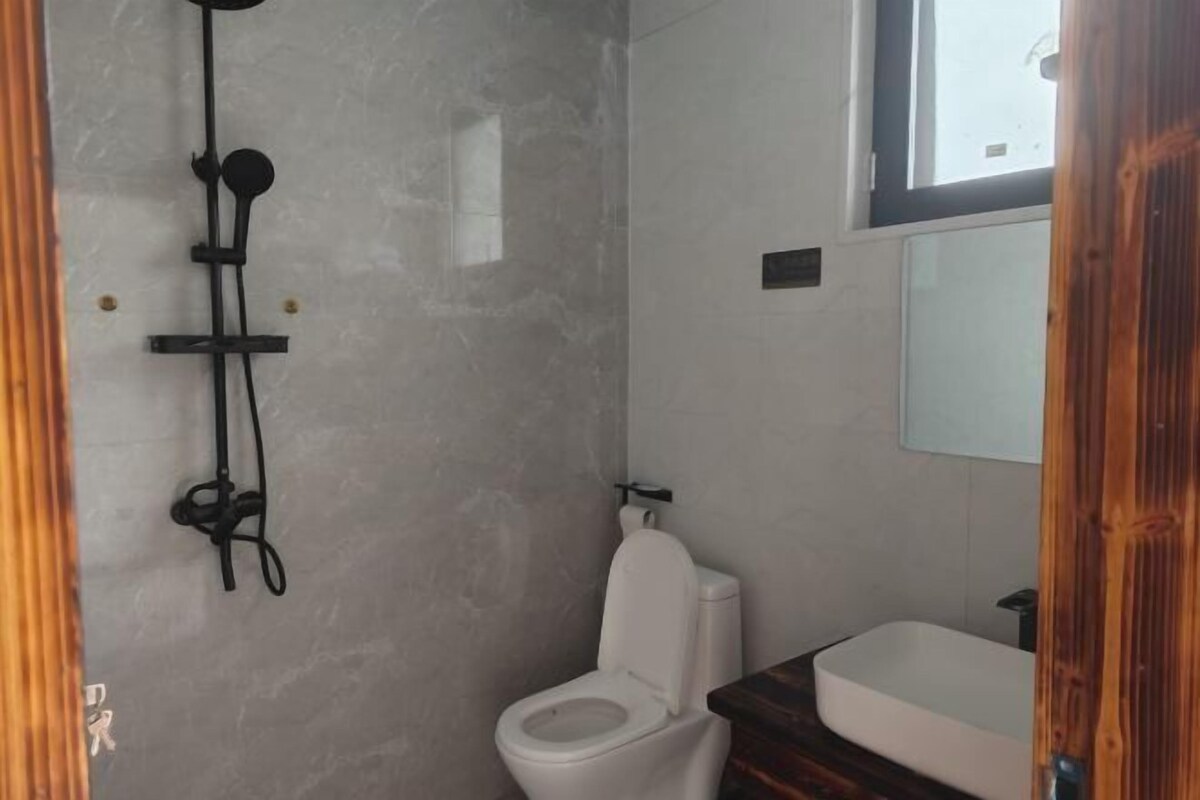 A bathroom with a toilet, a shower, and a sink.