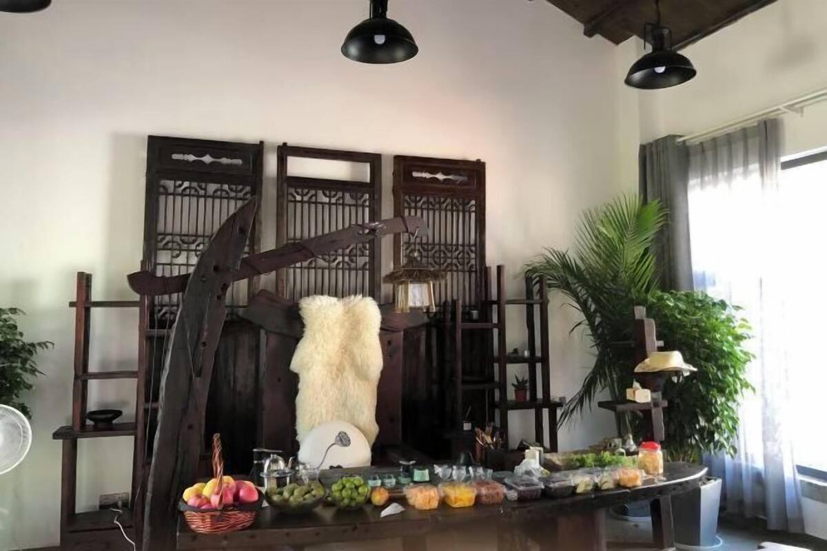 Une pièce avec une table en bois, dressée avec des fruits et des en-cas, un ventilateur et des objets décoratifs.