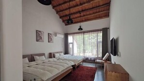 Ein Schlafzimmer mit zwei Betten, einem hölzernen Kopfteil, einem roten Teppich, einem Nachttisch aus Holz und einem an der Wand montierten Fernseher.