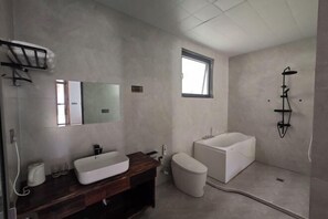 A modern bathroom with a large bathtub, a toilet, and a sink with a mirror. - Jinjiawan Guesthouse (Yifeng)