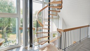 Una escalera de caracol con escalones de madera y barandillas negras que conduce a un piso superior.