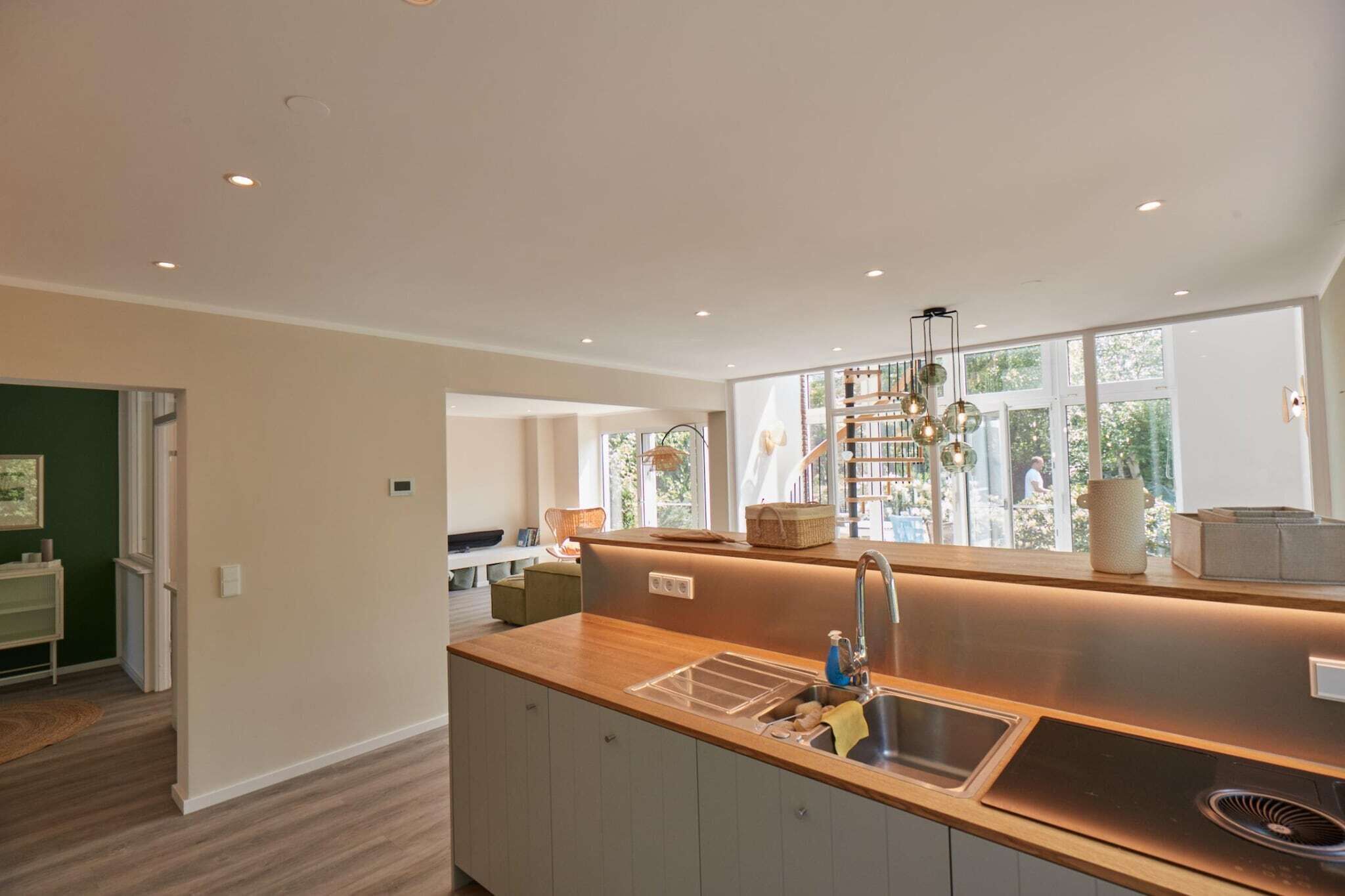 A modern kitchen with a wooden countertop, stainless steel sink, and a built-in range hood.