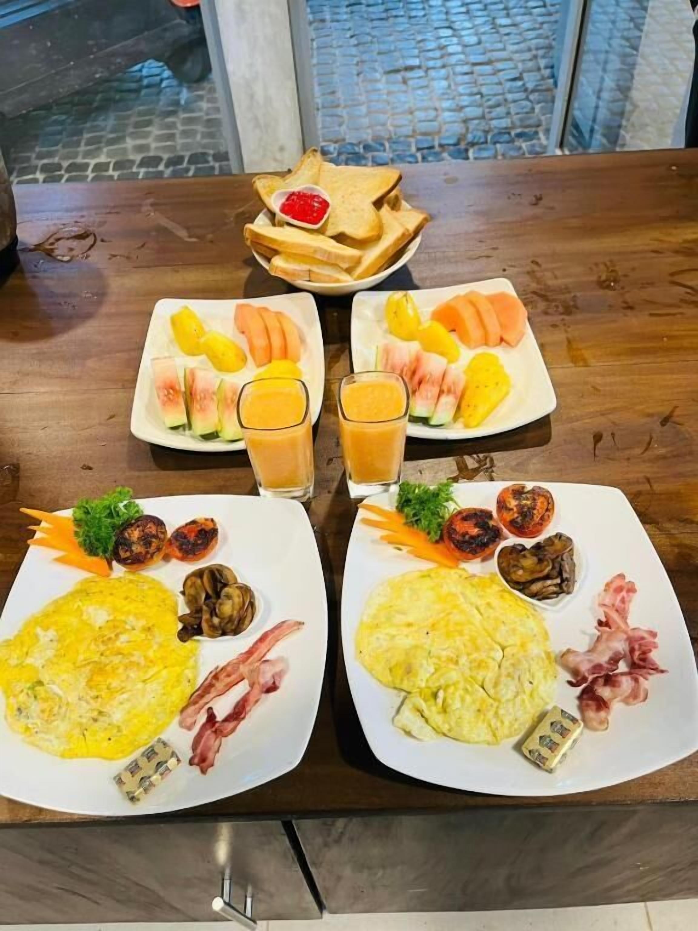 A dining table with two plates of food, including eggs, vegetables, and fruit.