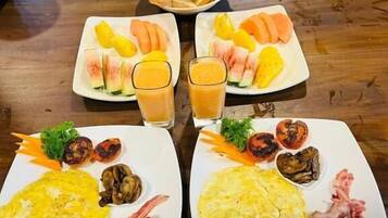 A dining table with two plates of food, including eggs, vegetables, and fruit.