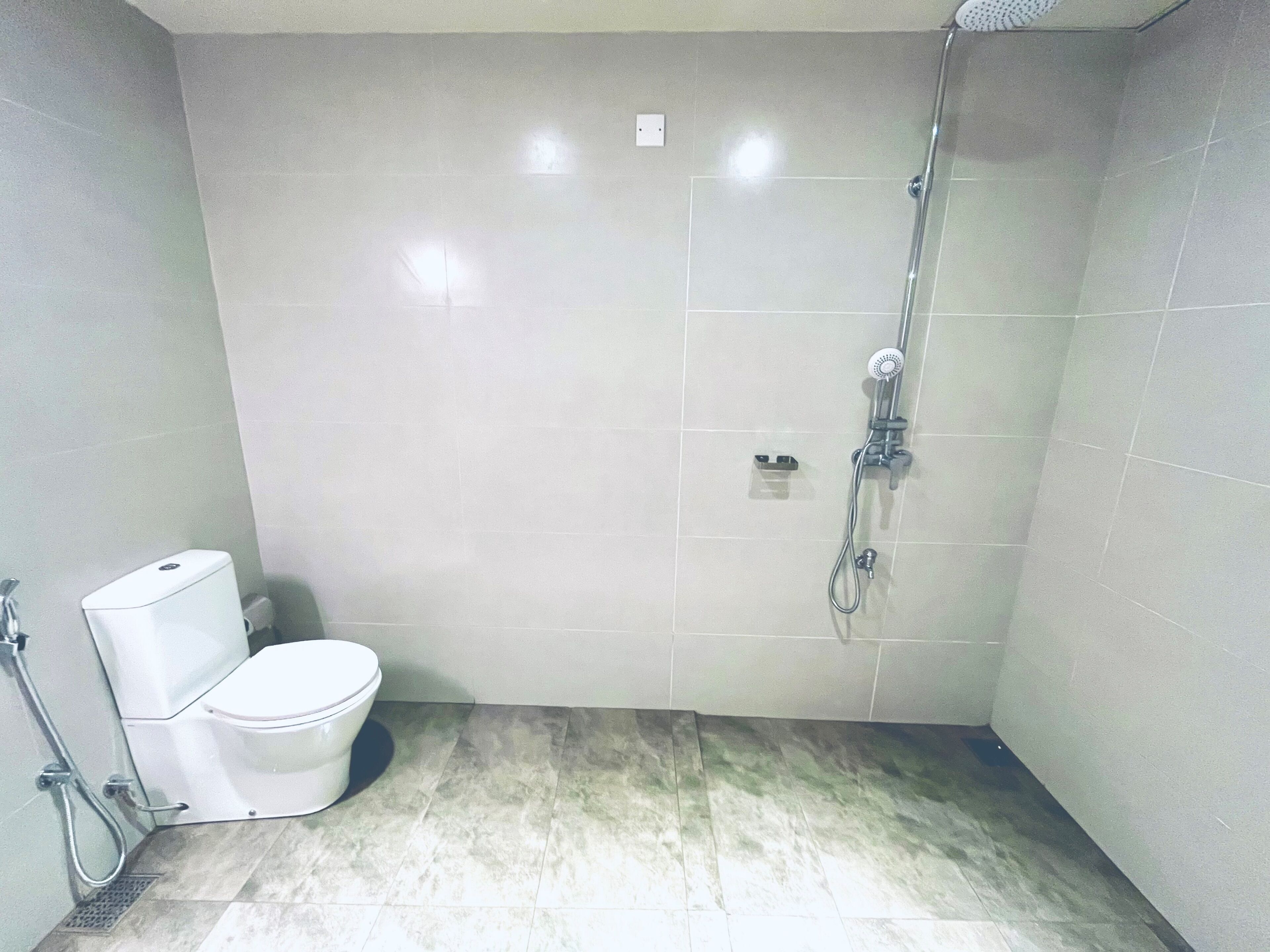 Un baño pequeño con azulejos, un inodoro, una ducha y un secamanos.