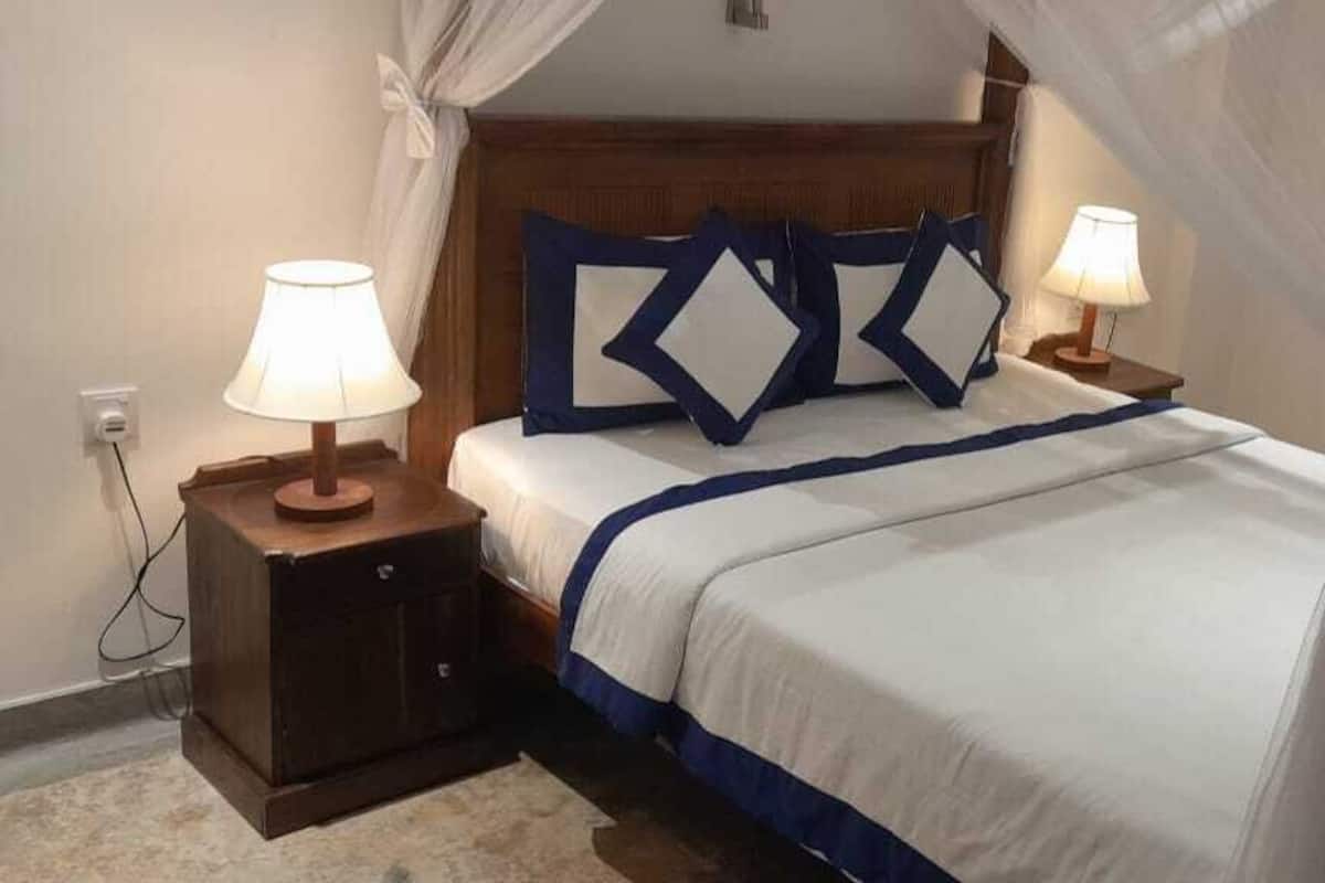 A neatly made bed with a canopy, two bedside tables with lamps, and a wooden headboard.