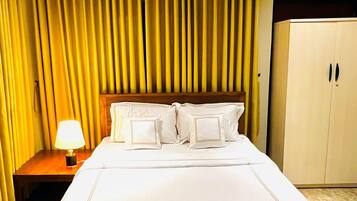Una habitación de hotel con una cama grande, una mesita de noche con lámpara y un armario.