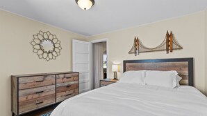 Une chambre à coucher avec un grand lit, une commode, un miroir et un élément décoratif mural.