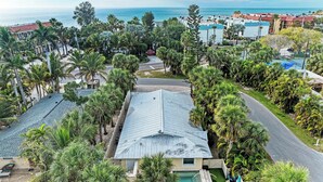 Ein Wohngebiet mit einem Haus, das einen Swimmingpool hat, umgeben von Palmen und Blick auf den Ozean.