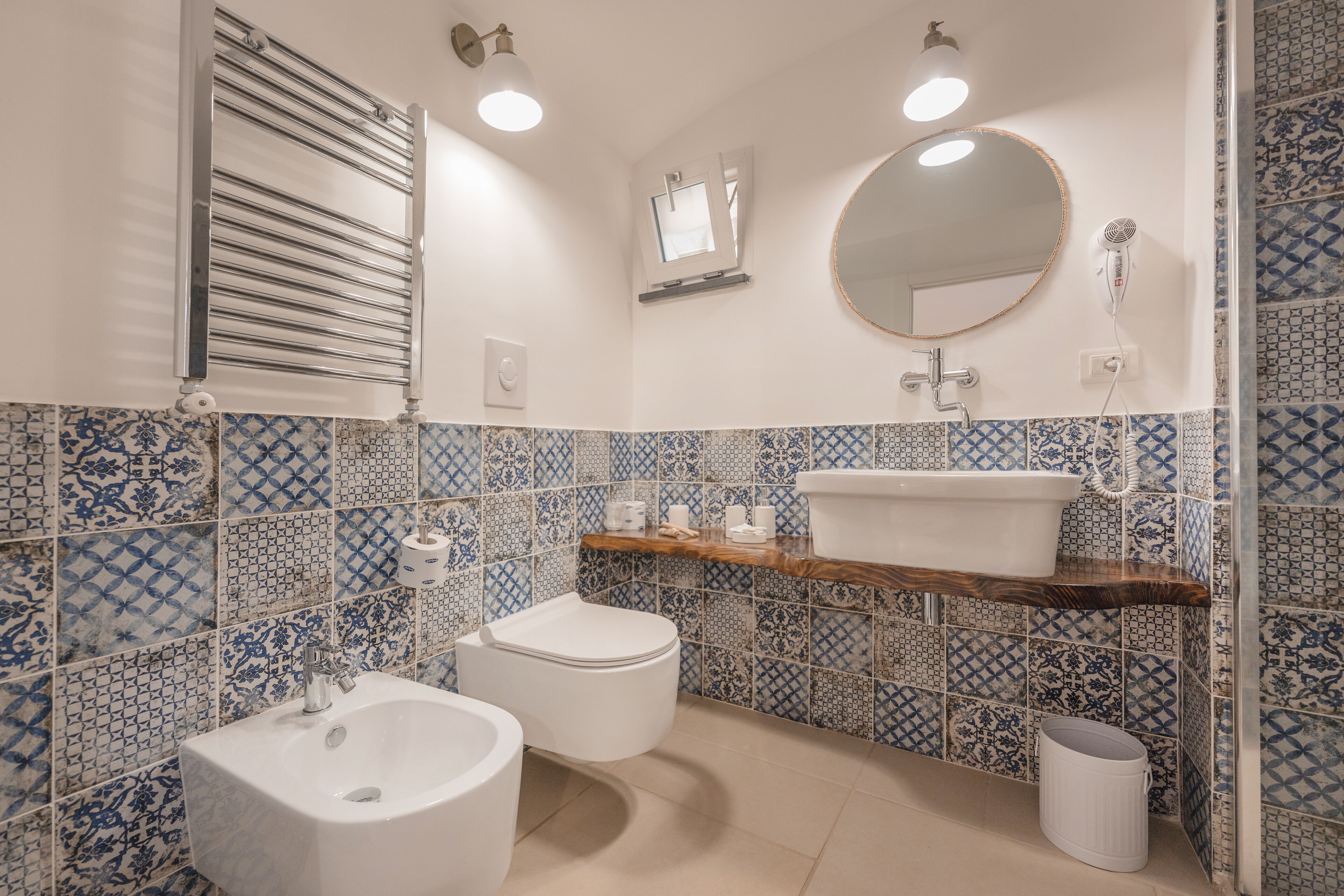 Un baño con un lavamanos blanco, un inodoro, un espejo y una zona de ducha.