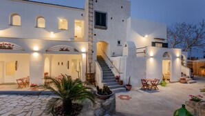 A modern building with a staircase, outdoor seating, and potted plants. - Calacala rooms, restaurant & farm experience (Procida)