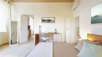 Habitación de hotel con cama, escritorio y silla. Hay un cuadro en la pared y un equipo de aire acondicionado.