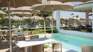 A poolside area with multiple tables and chairs, surrounded by umbrellas. - Calacala rooms, restaurant & farm experience (Procida)