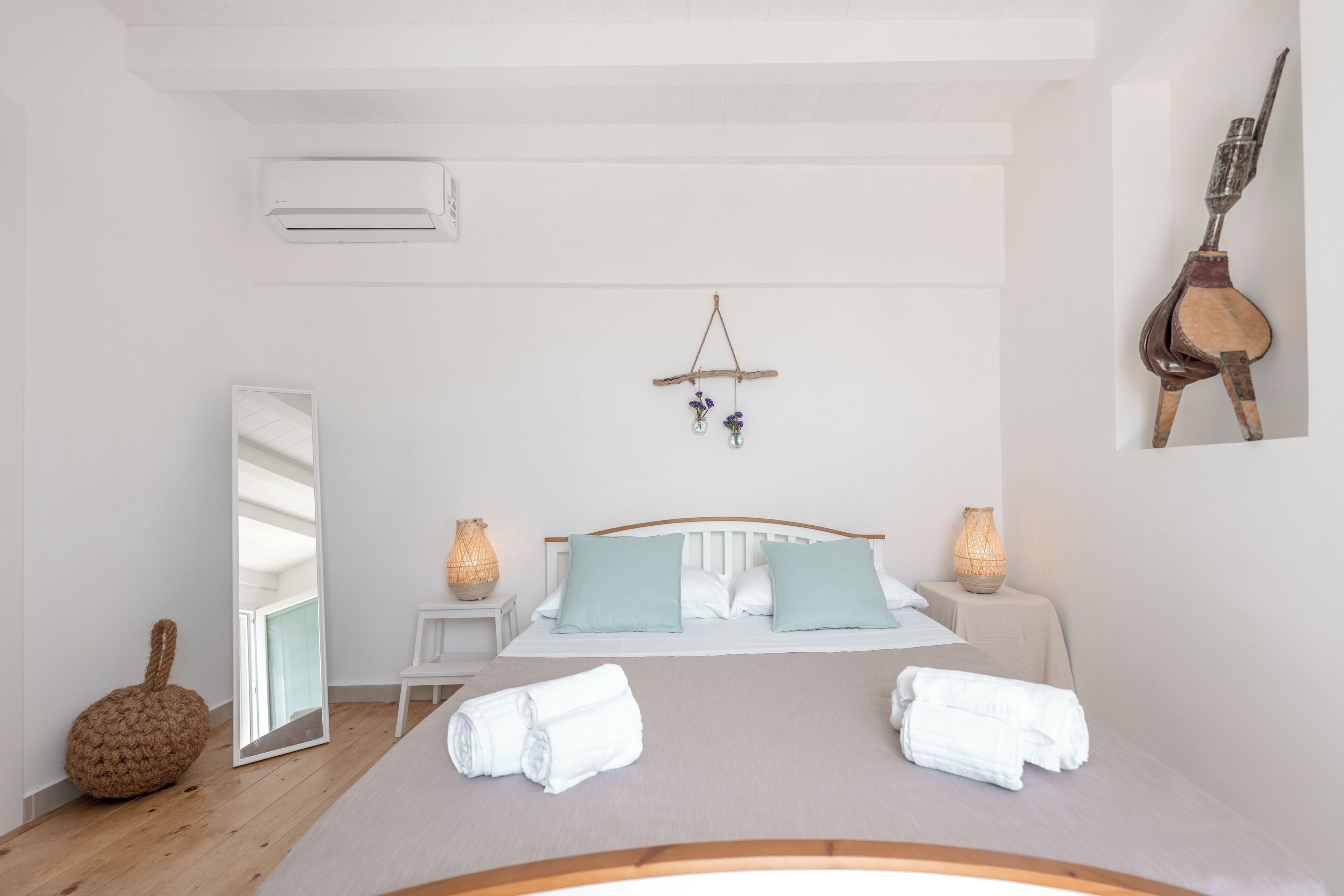 Un dormitorio con cama, mesitas de noche, un espejo y una planta colgante.