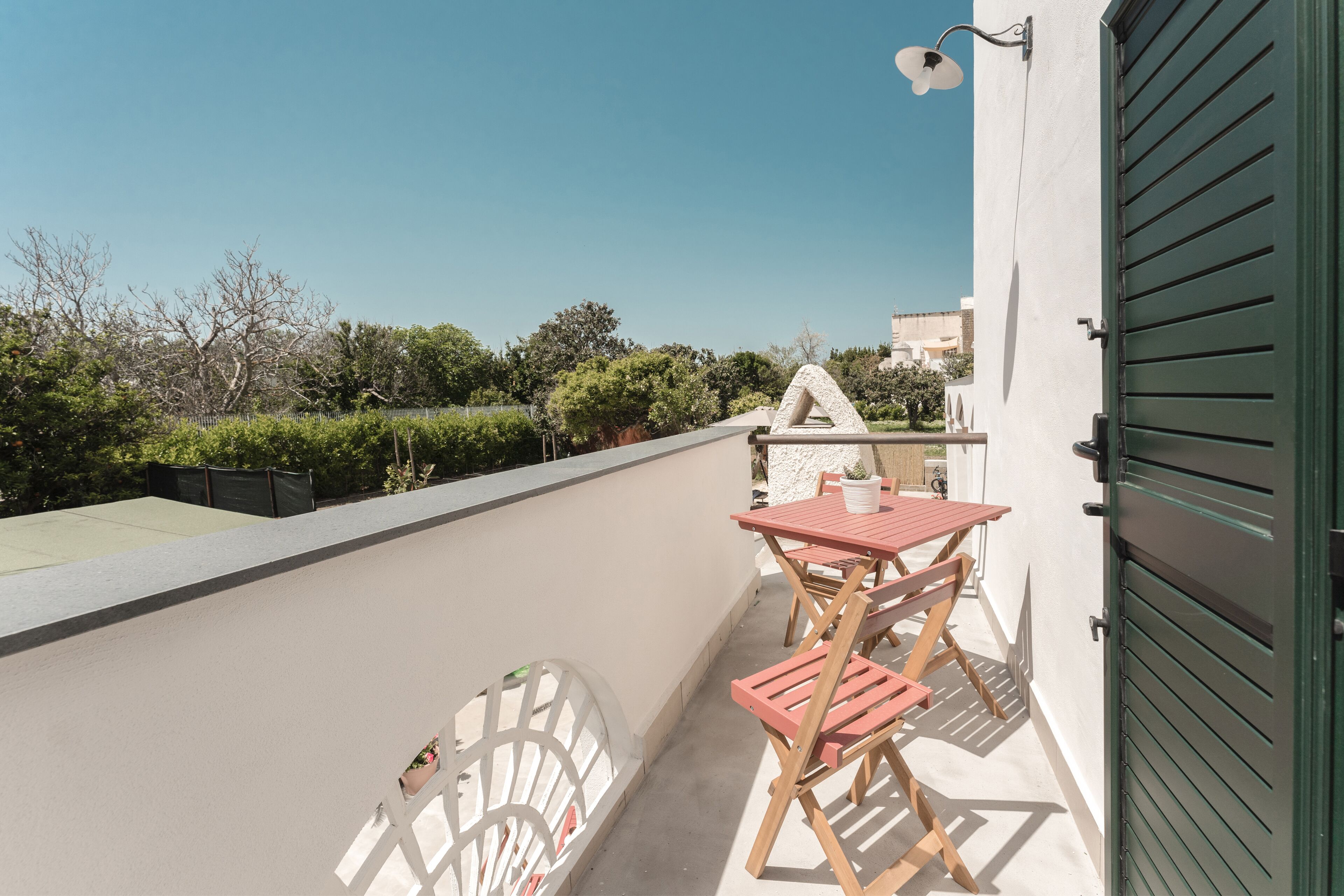 A balcony with a table and chairs, a potted plant, and a view of the surrounding area.