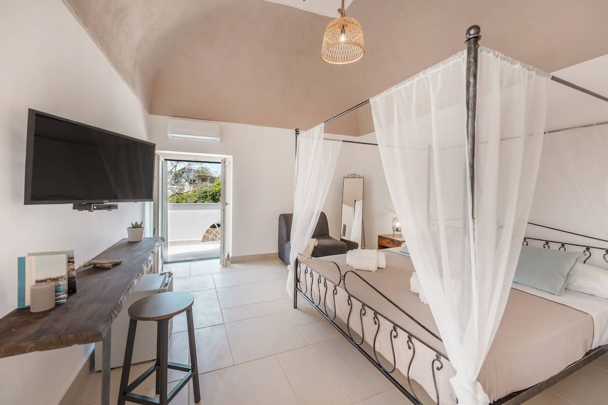 A bedroom with a bed, a TV, a desk, and a chair.