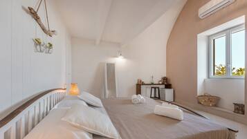 Un dormitorio con cama, mesita de noche, espejo y ventana.