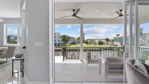 A modern living room with a balcony, a dining area, and a view of a residential area. - Private Pool- Canal Front- Outdoor Bar- 5BR Sunsational Sunsets (Fort Myers Beach)