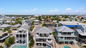 A coastal residential area with multiple houses, a swimming pool, and a clear view of the ocean. - Private Pool- Canal Front- Outdoor Bar- 5BR Sunsational Sunsets (Fort Myers Beach)