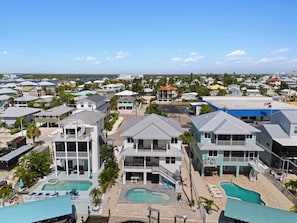 Una zona residencial costera con varias casas, una piscina y vista despejada al océano.