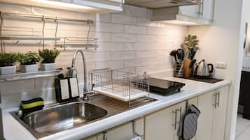 Een koelkast, een magnetron, een waterkoker, kookgerei, borden en bestek