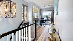 Un intérieur moderne avec un escalier, un espace bureau et une vue à travers une porte vitrée.