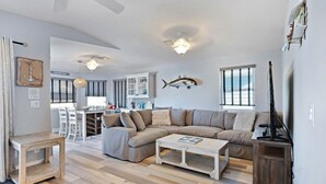 Un salon spacieux avec un grand canapé d’angle beige, une table basse en bois et un coin repas à l’arrière-plan.