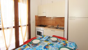 Une cuisine compacte comprenant une table à manger pour deux personnes, une cuisinière, un four et un évier.