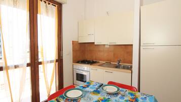 Lemari es besar, peralatan masak/sendok-piring, dan meja makan