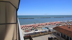 Une vue sur la plage depuis un balcon, avec des parasols et des chaises de plage.