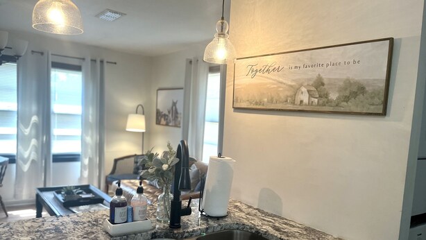 A kitchen with a double sink, granite countertop, and a wall-mounted picture with a quote. - Farmhouse - Centrally Located in Great Bend, Gas Firepit and Pet Friendly Yard (Great Bend)