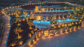 An aerial view of a luxury resort with multiple swimming pools, stone architecture, and landscaped gardens.