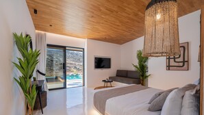 Un dormitorio moderno con una cama grande, un televisor y vistas a un paisaje montañoso.