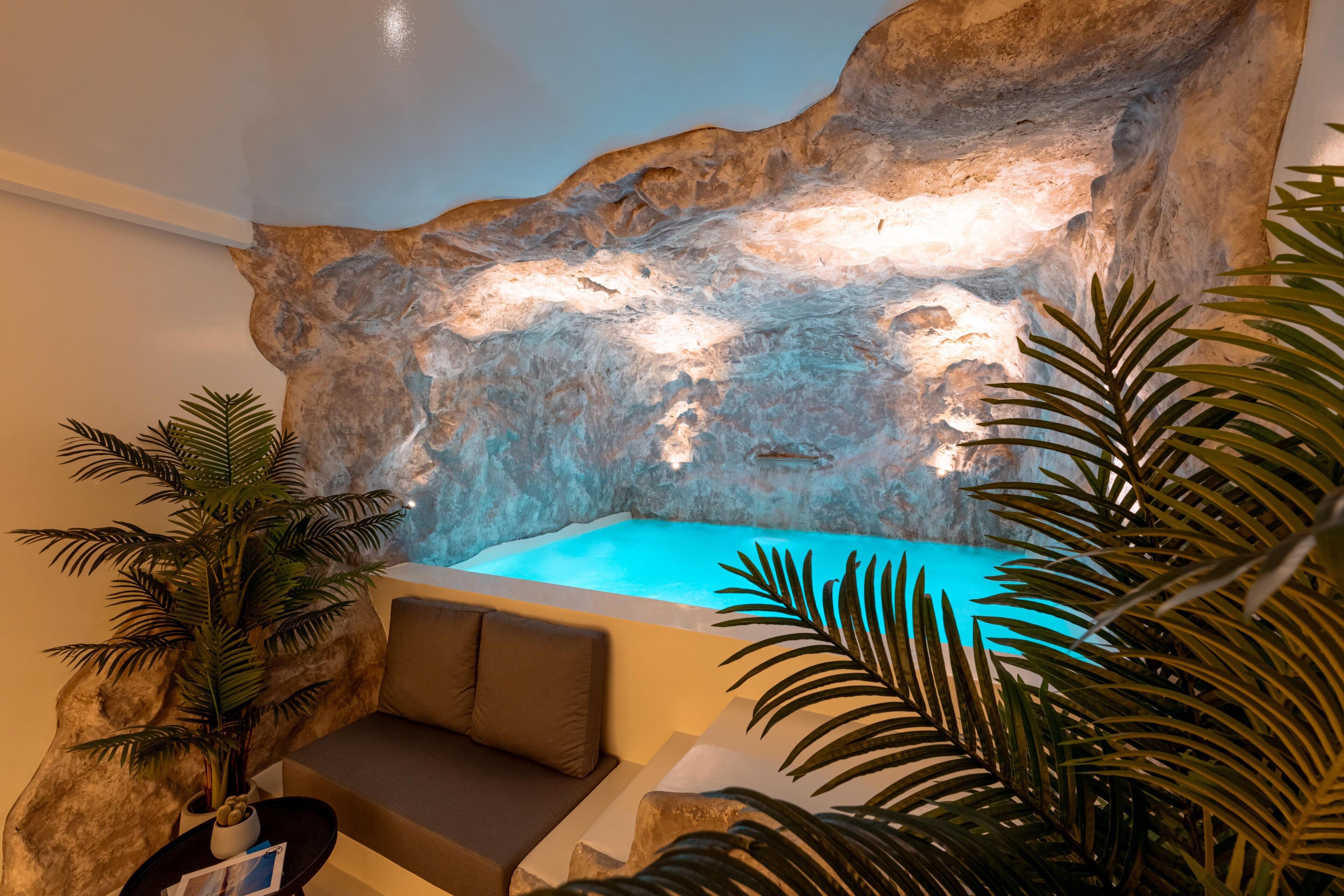 A spa area with a hot tub, a rock wall, and a seating area with a plant.