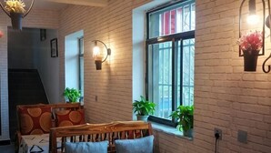 A cozy room with a brick wall, a wooden bed, a window with plants, and a wall-mounted light fixture. - Water Ink Yuanyang Hotel Yuanyang (Yuanyang)