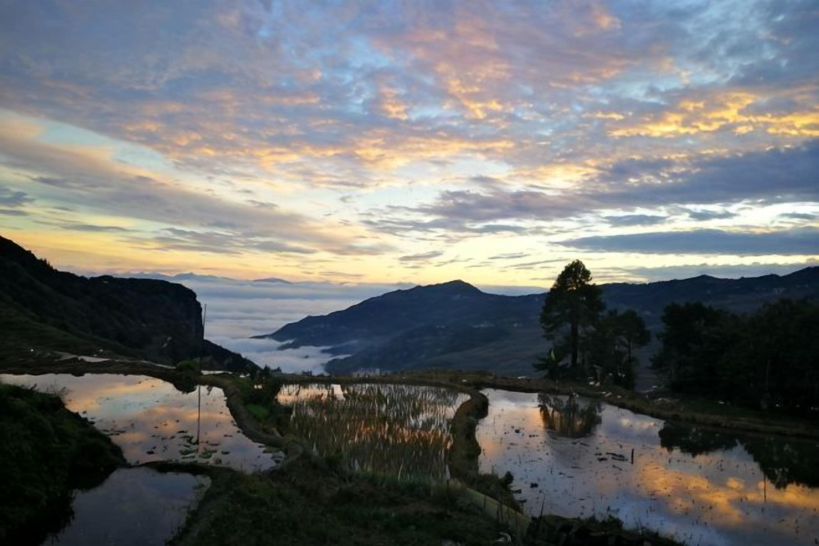 A natural landscape with a body of water, hills, and a cloudy sky.