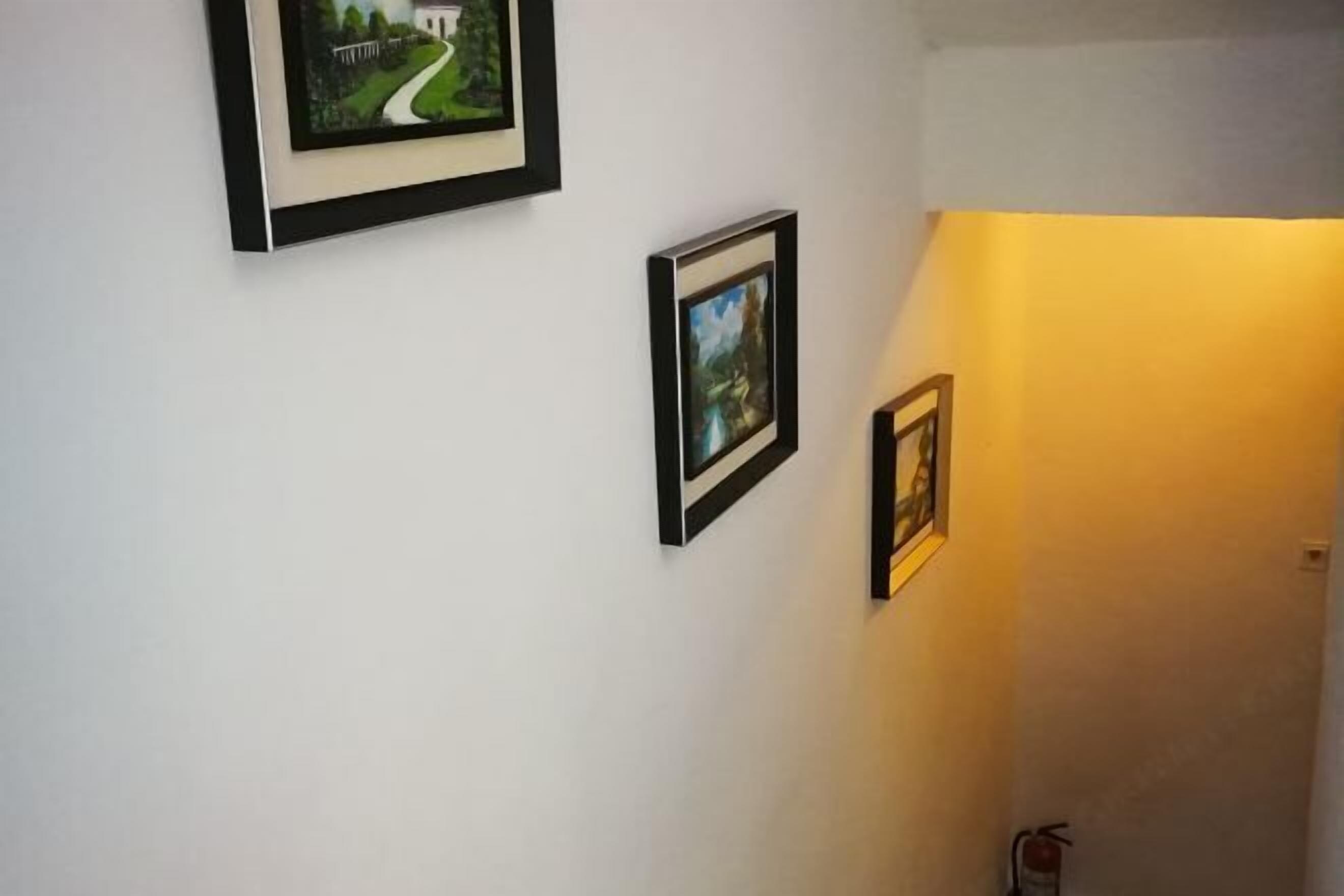 Een gang met drie ingelijste foto's aan de muur.