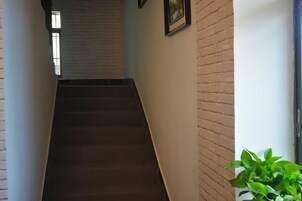 Una escalera que lleva a una habitación con pared de ladrillo y una planta en maceta.