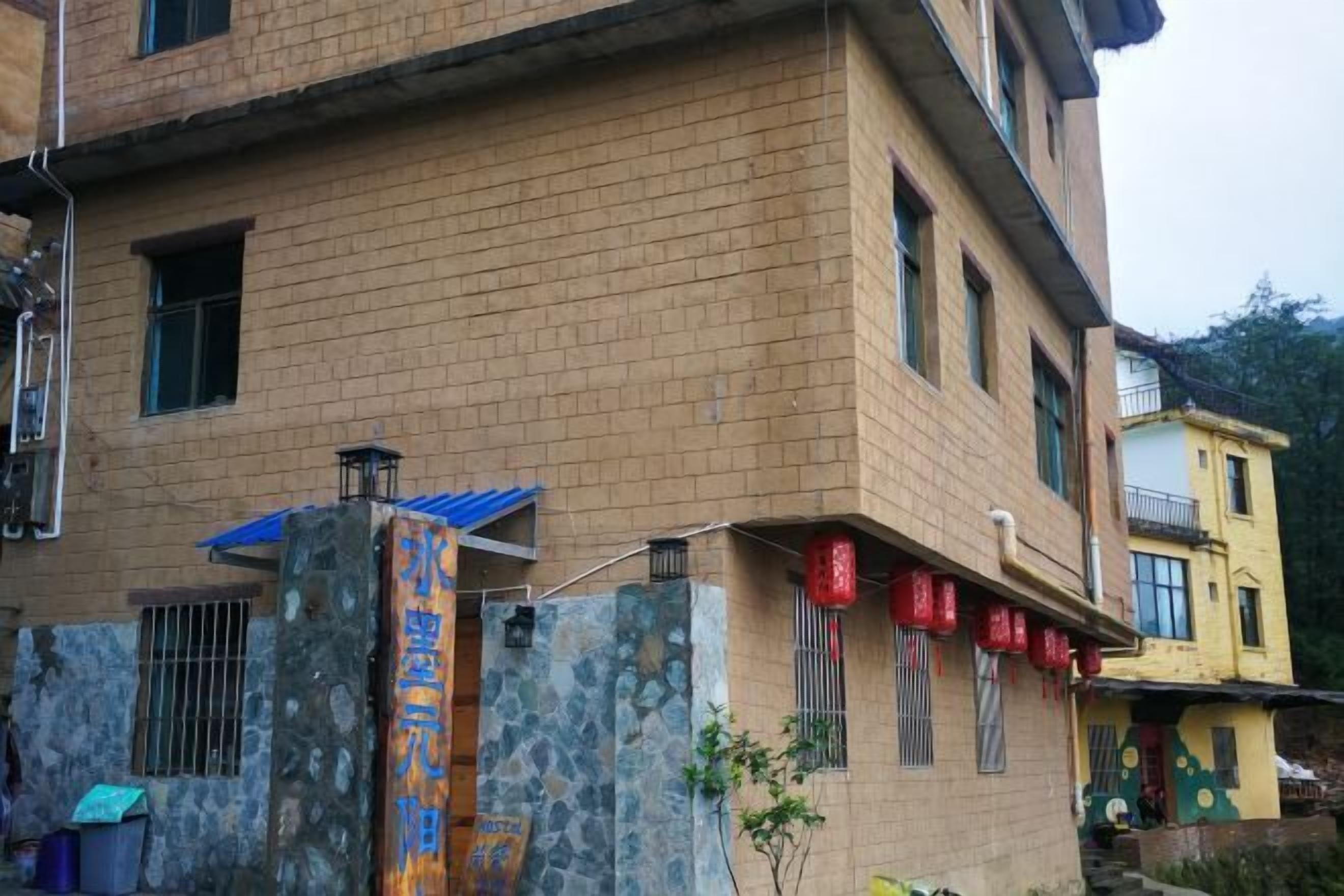 A multi-story building with a stone facade, a blue awning, and a sign with Chinese characters.