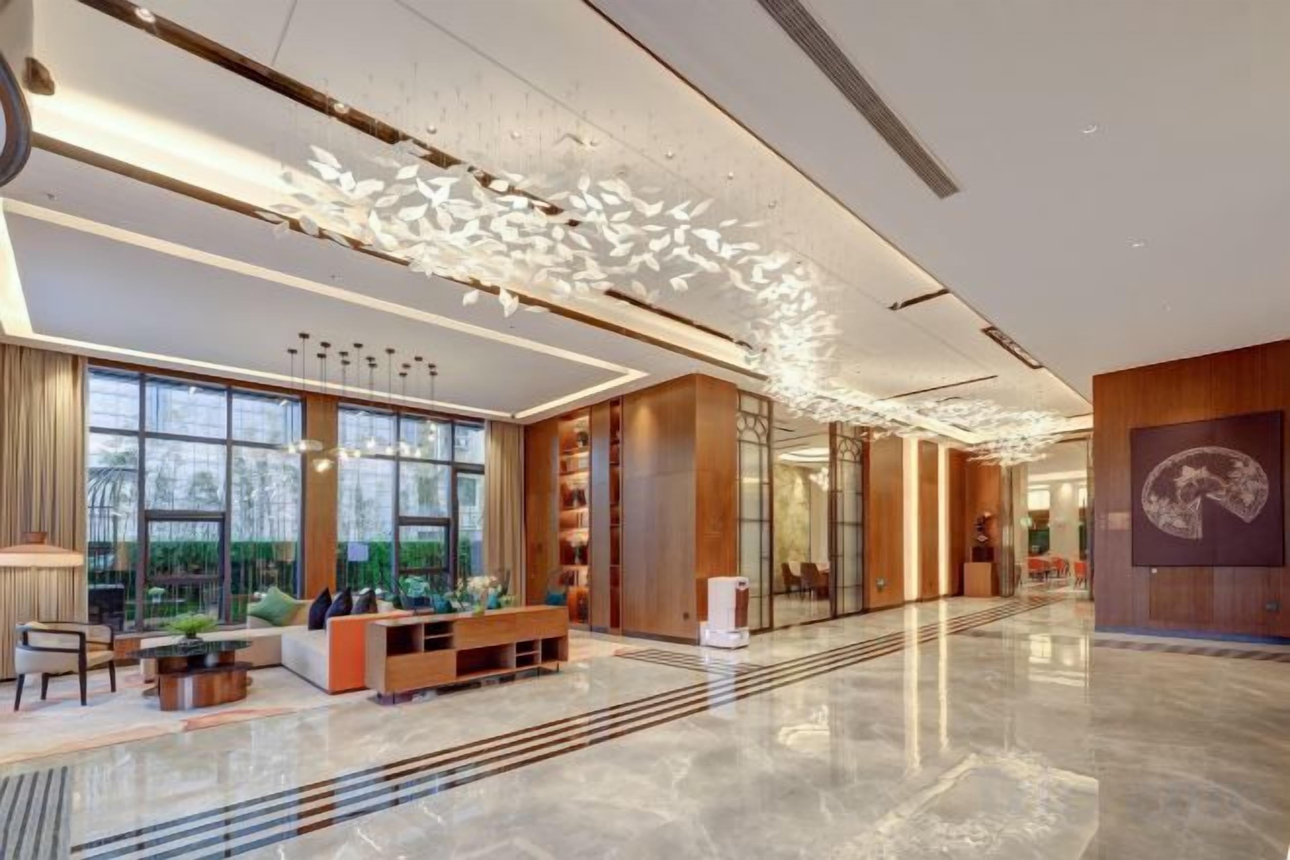 A modern hotel lobby with a reception desk, seating area, and large windows.